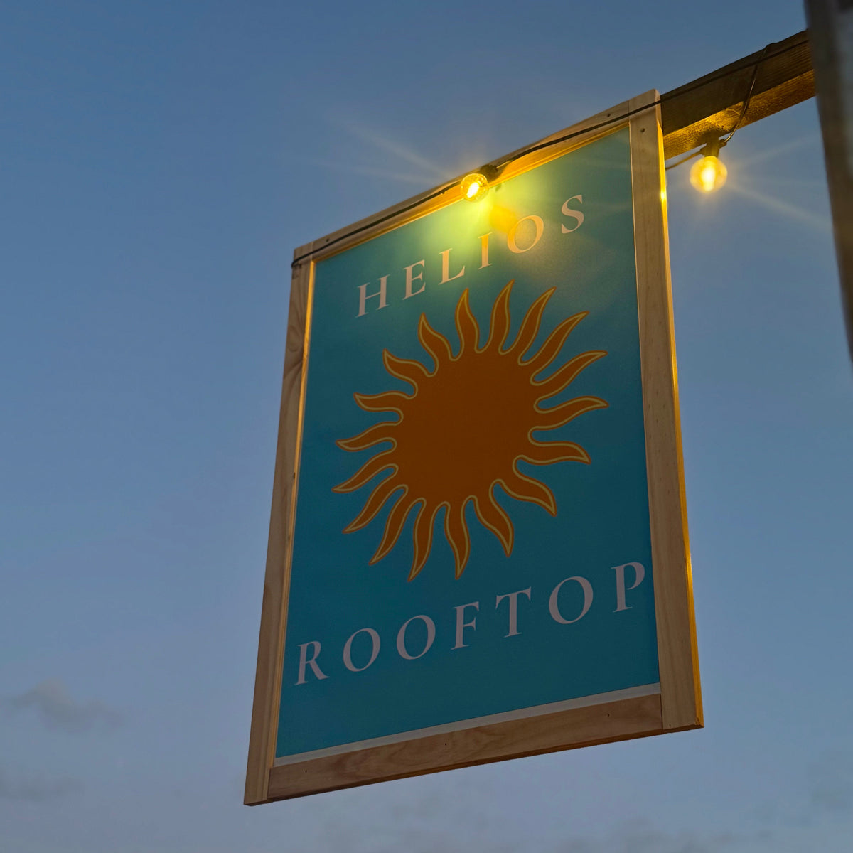 Helios Rooftop sign with sun logo against a twilight sky