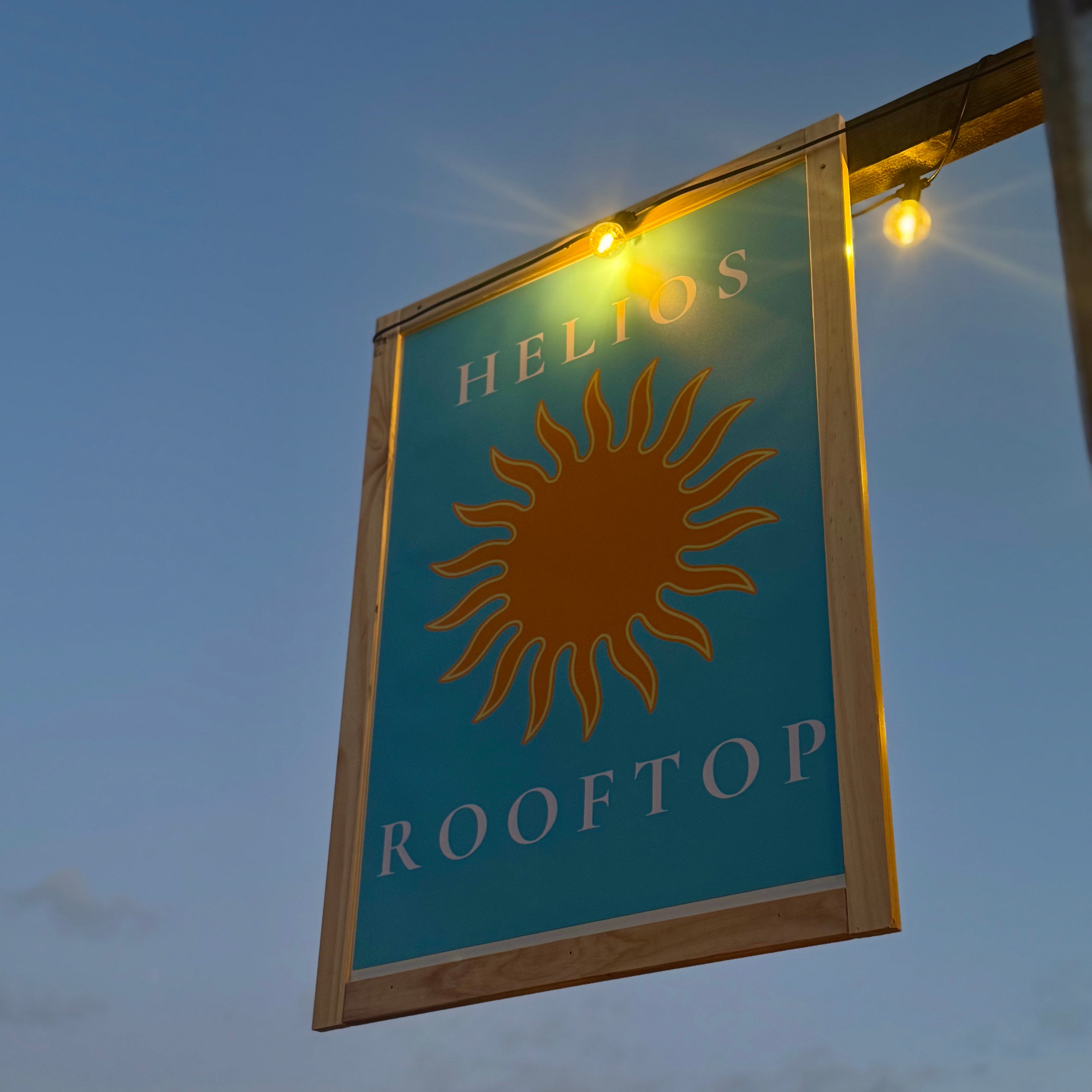 Helios Rooftop sign with sun logo against a twilight sky